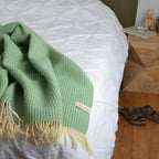 Bild mit der Decke Weltenburg in der Farbe Kiefernnadel auf einem Bett