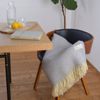 Bild mit der Decke Weltenburg in der Farbe Dolomit am Esstisch auf einem Stuhl liegend