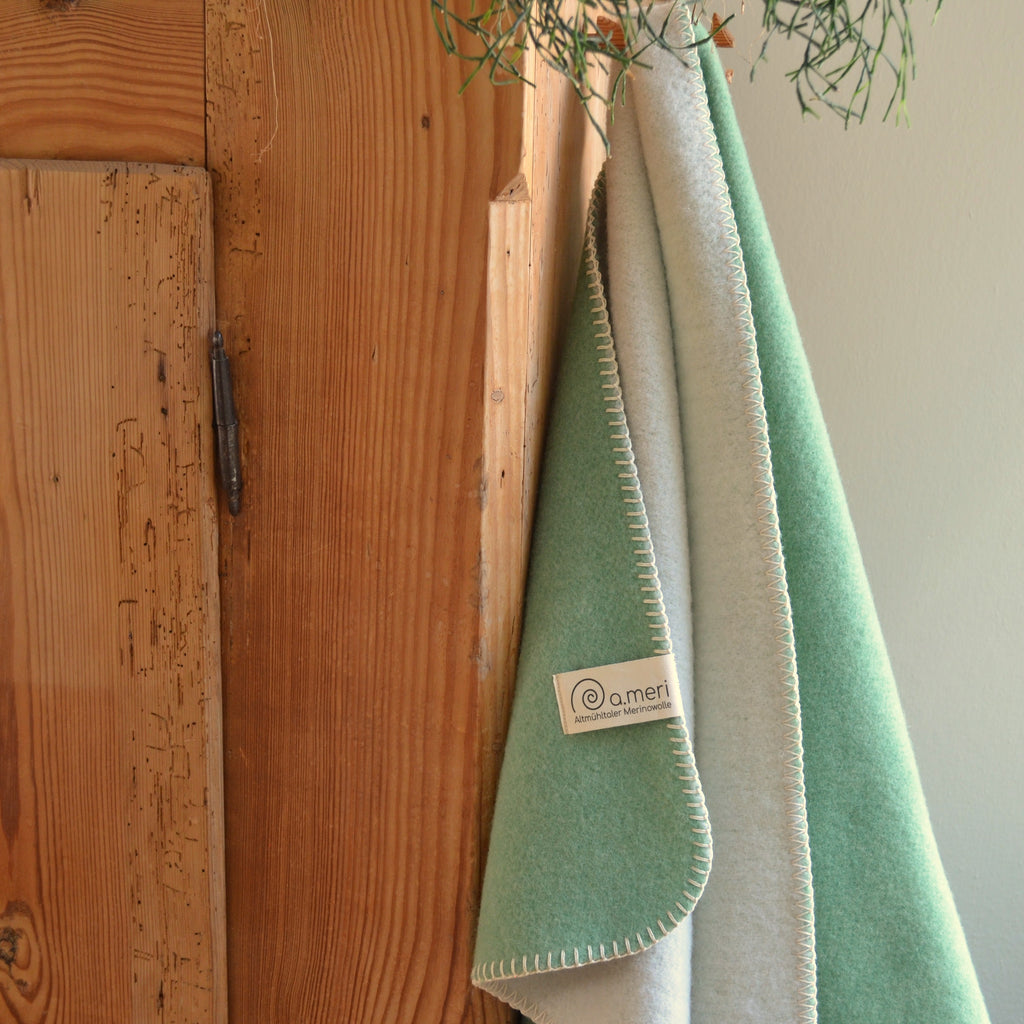 Bild mit der Decke Eggersberg in der Farbe Kiefernnadel/Heller Jurafels. Decke hängt an einem Schrank. 