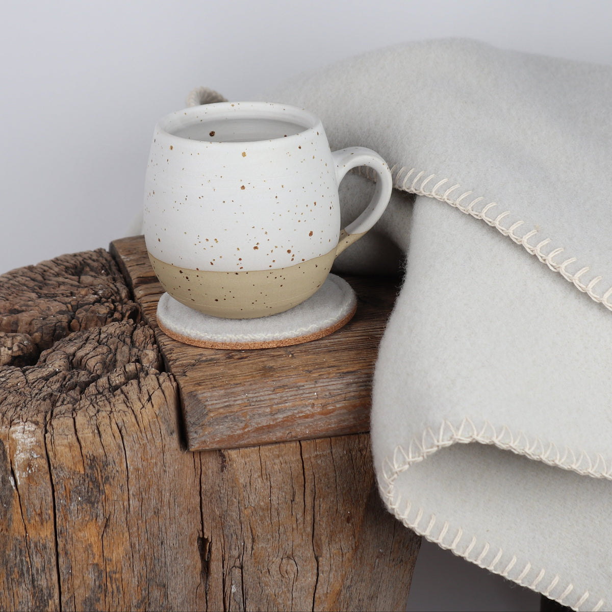 Bild des Wolluntersetzer Painten auf einer Holzbank mit einer Tasse und einer Decke