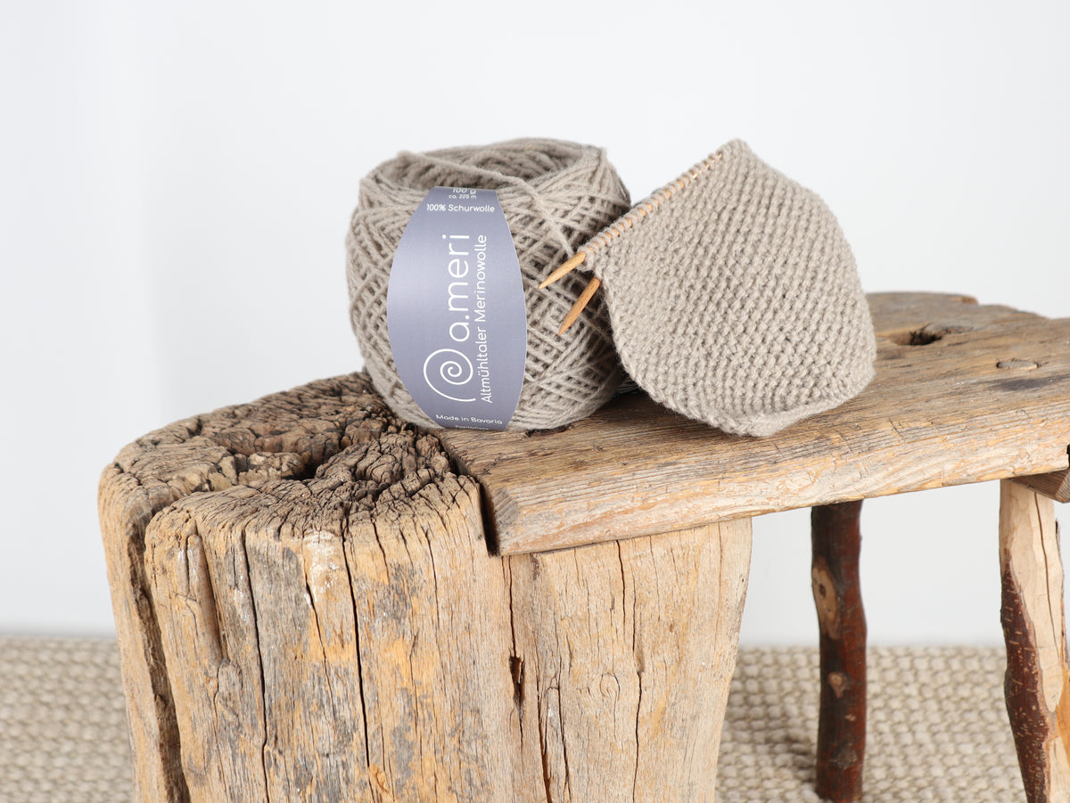 Strickprojekt mit Wollknäuel Dollstein auf einem Holzschemel